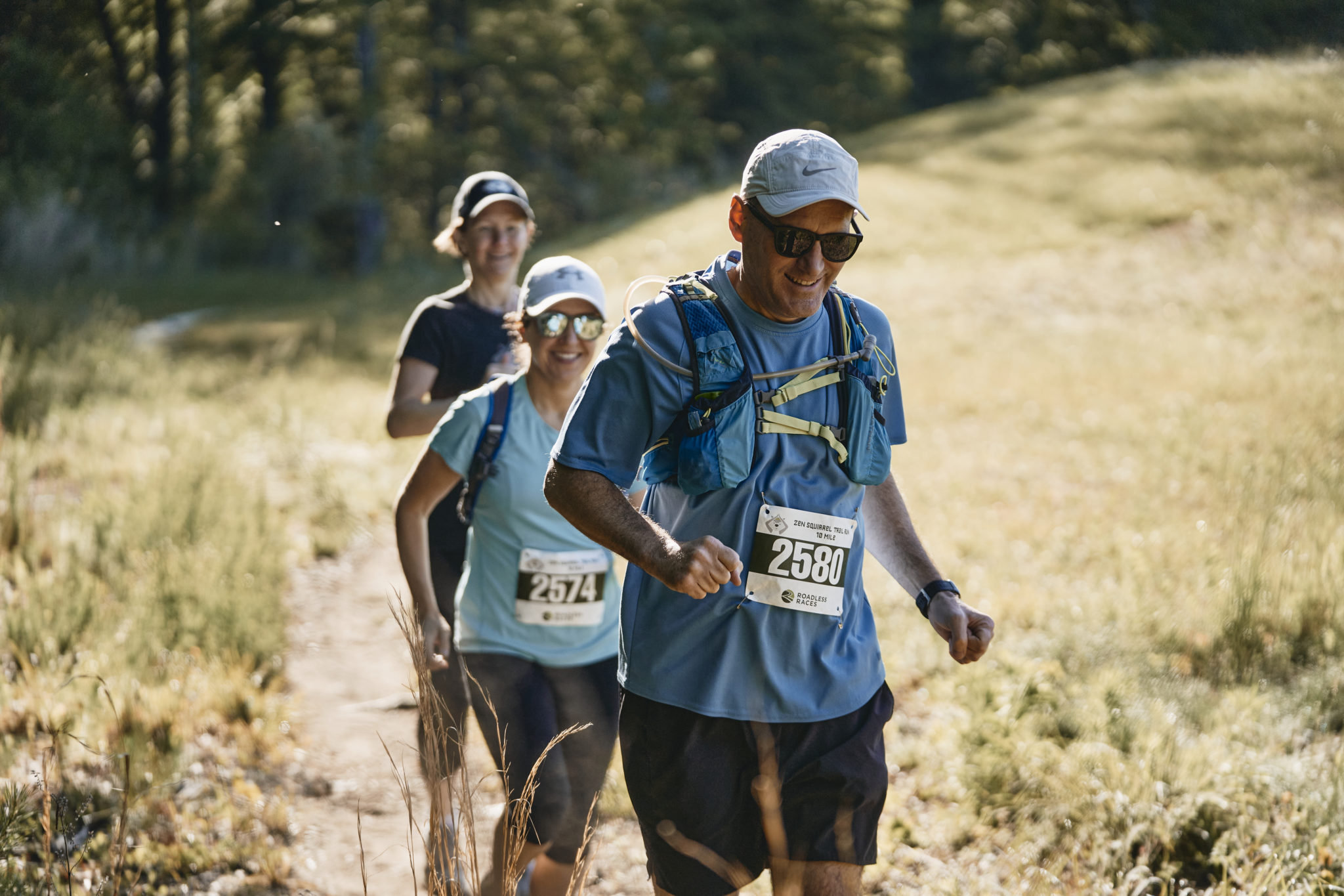 three people running on a trail
